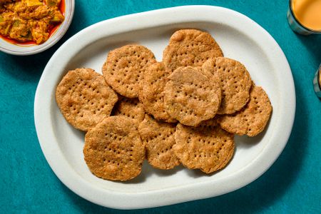 A platter of mathri, served with chai tea and chutney