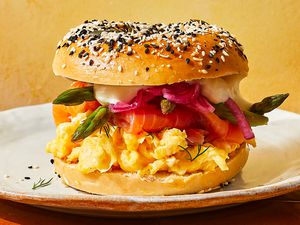 A Smoked Salmon Breakfast sandwich served on an everything bagel with asparagus, scrambled eggs, smoked salmon, dill, pickled red onions, and cream cheese