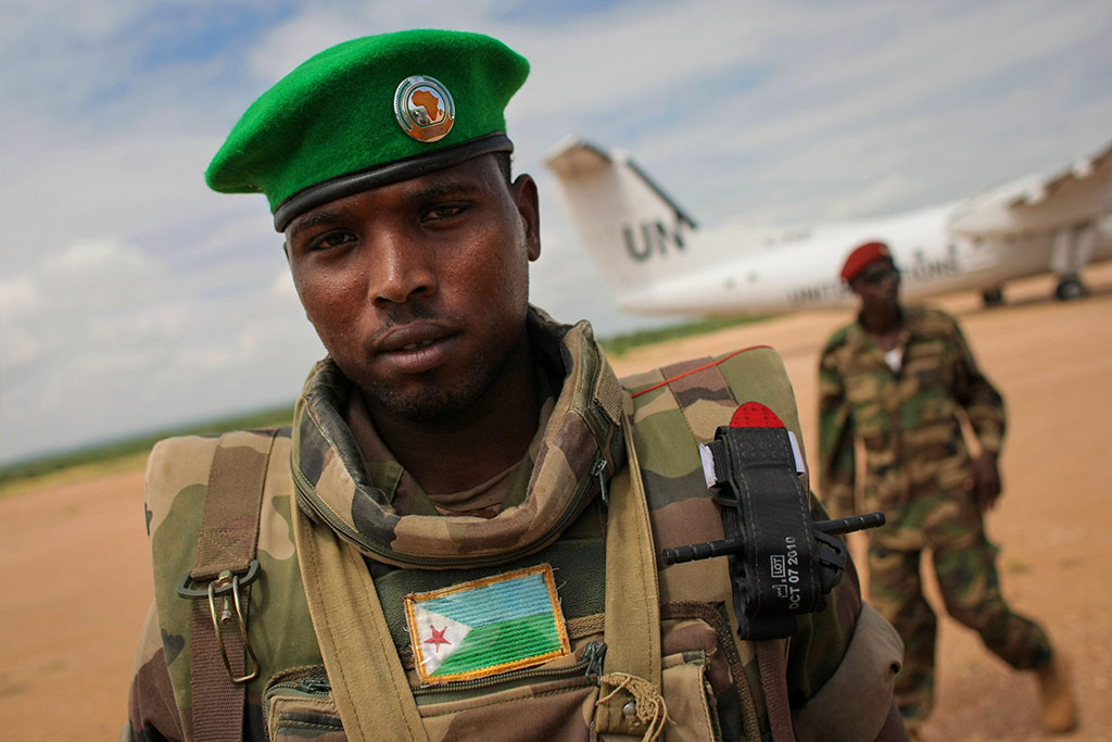 Un soldat du contingent djiboutien servant au sein de la Mission de l’Union africaine en Somalie (AMISOM) monte la garde tandis qu’un avion des Nations Unies se prépare à décoller de l’aéroport de Belet Weyne. Photo : UA/Stuart Price