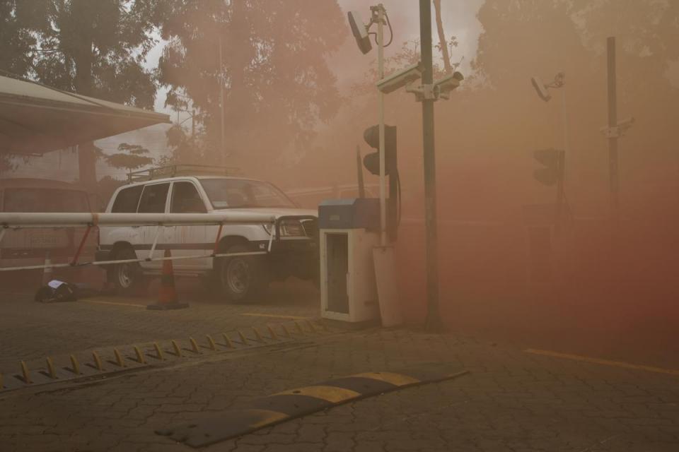 A car is stuck on the road with smoke all around it.