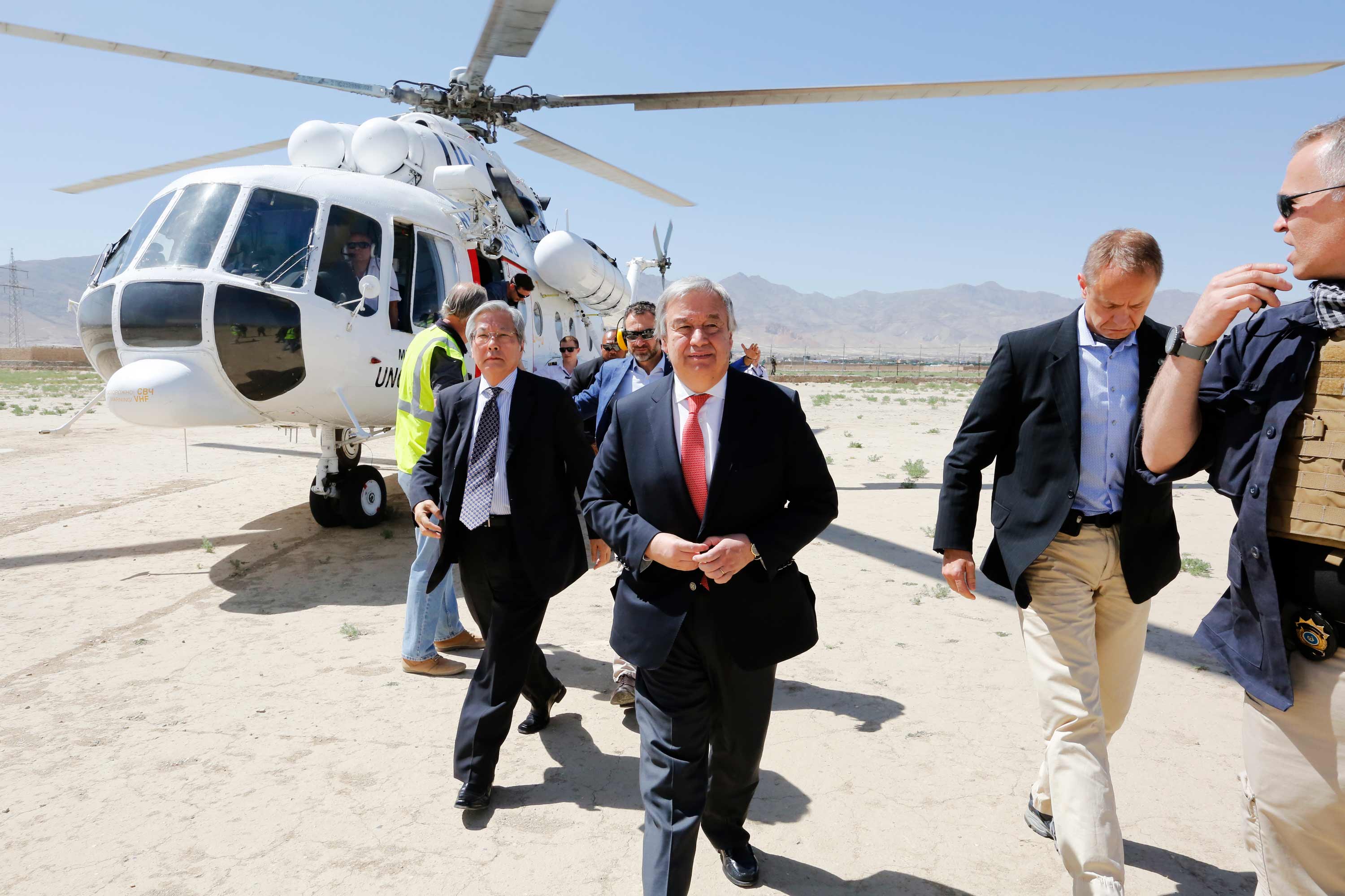 UN Secretary-General walks in an airport runway surrounded by security officers among others.