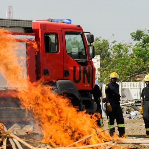 UN security officers tend to a fire with a red UN firetruck in view.