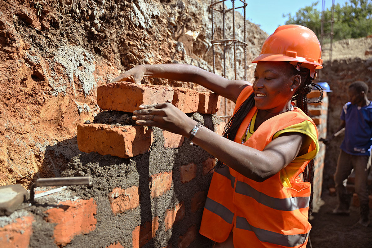 Woman layering bricks for her house