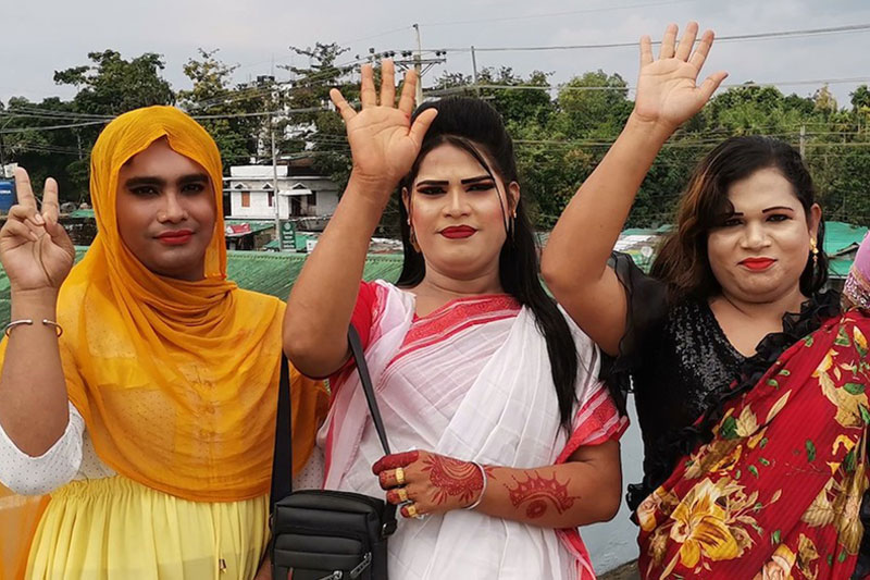 three people dressed in colorful clothes raise their hand to the air and one of them indicates the sign of victory