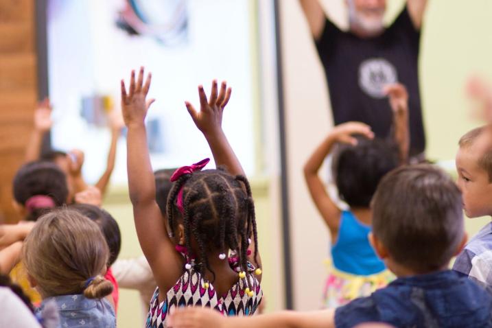 Children raise their hands in a classroom