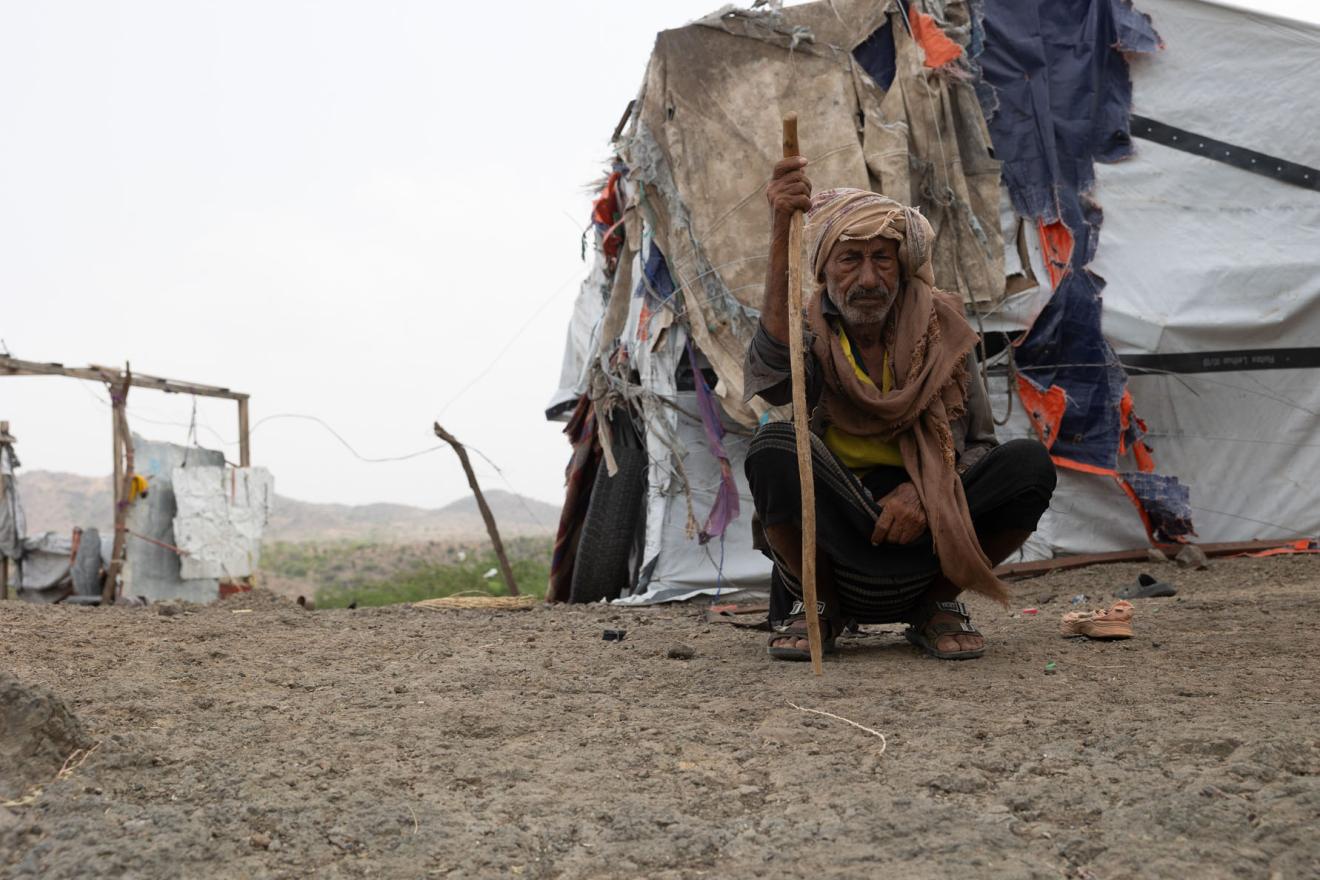 Un homme se tient devant une tente de fortune