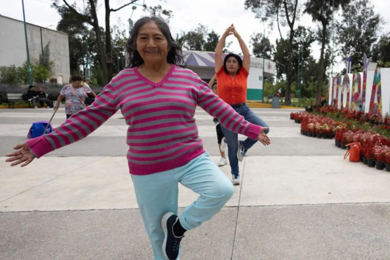 Varias mujeres realizan ejercicio físico aeróbico en un parque urbano. 