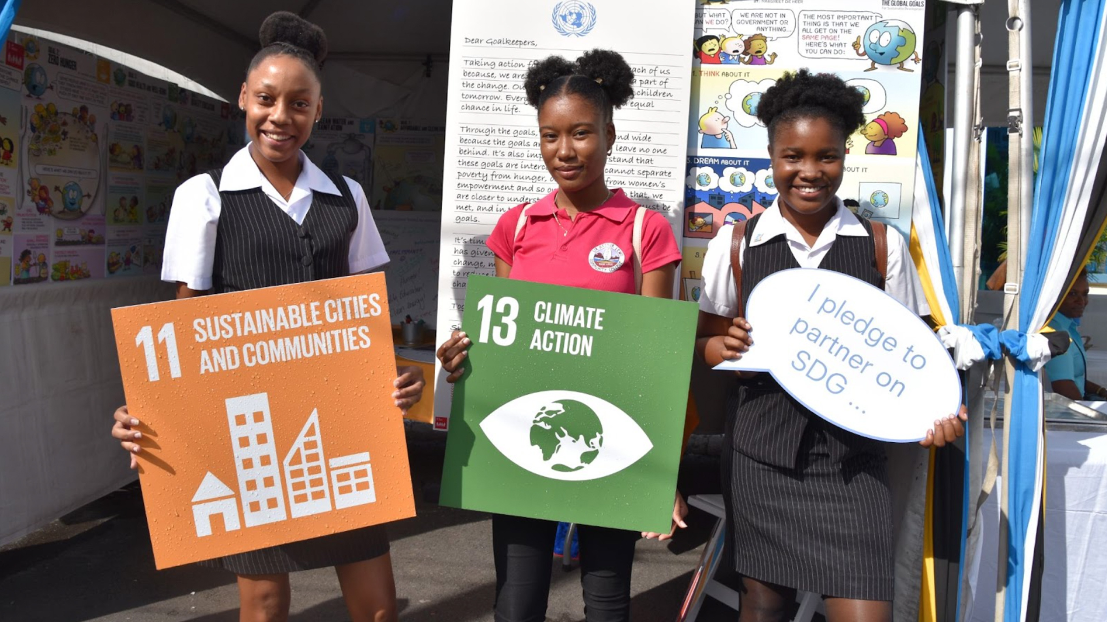 3 girls holding sdgs signs