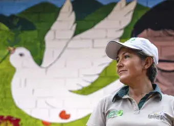 A woman stands in front of a painting of a dove. 