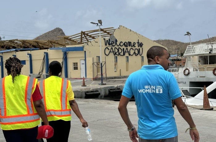 A member of the UN Women’s deployment team is seen walking past a damaged building in Grenada.