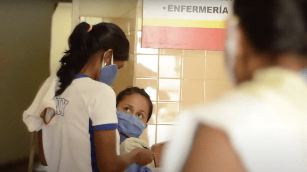 A woman speaks with a nurse.