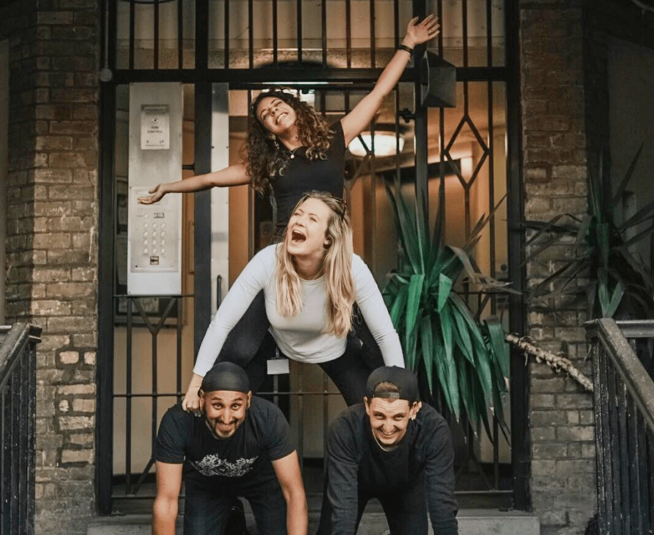 Diverse group of four having fun at a pub crawl and creating a human pyramid