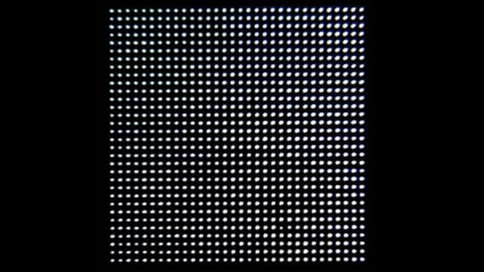 Close-up view of a grid pattern of round, uniformly spaced white dots on a black background