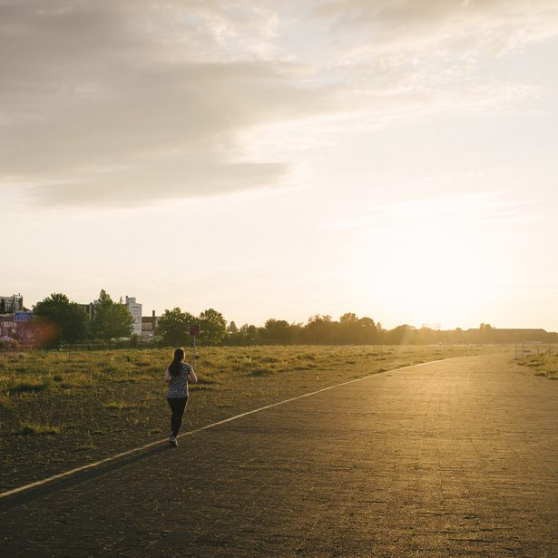 Läuferin auf dem Tempelhofer Feld joggt der Sonne entgegen