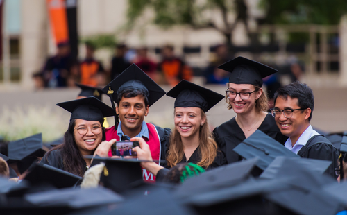 Photo: Students taking a selfie in graduation caps at MIT graduation. All smiling.