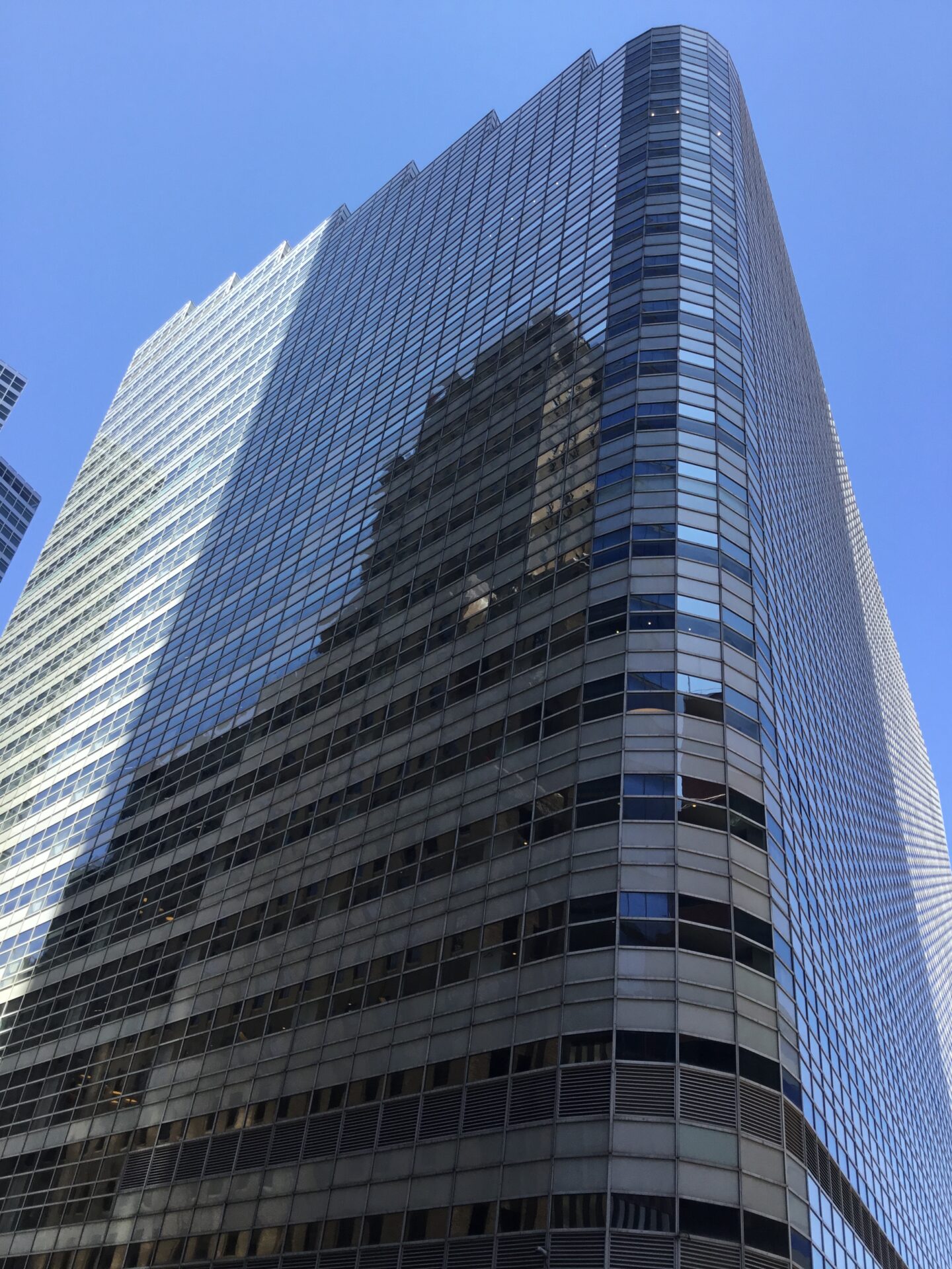 Large bank building as seen from ground level towering into a clear blue sky