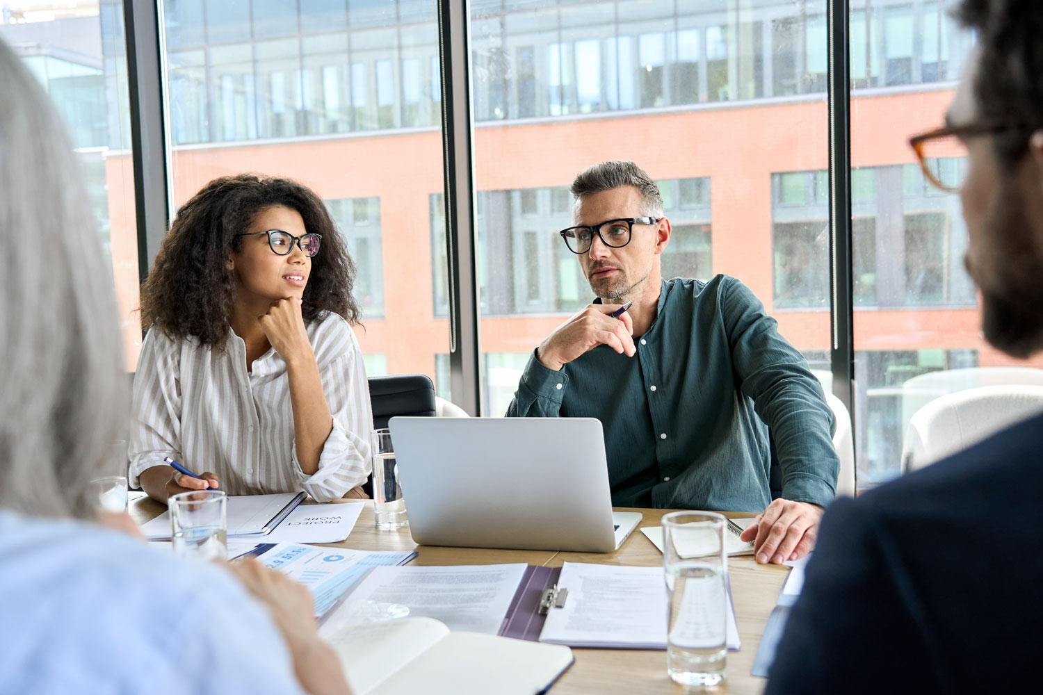 group of people meeting in an office and discussing over paperwork