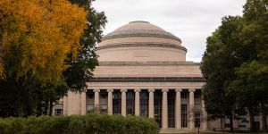 A photo of MIT's Killian Court with the Great Dome in the center of the image and trees surrounding