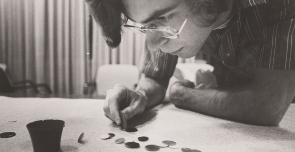 Closeup of a man leaning over a table with an array of winks. He appears to be concentrating on a shot.