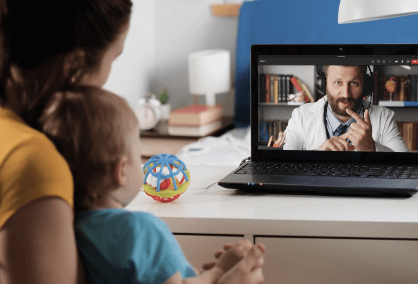 Caregiver and child interacting with a clinician on a laptop.