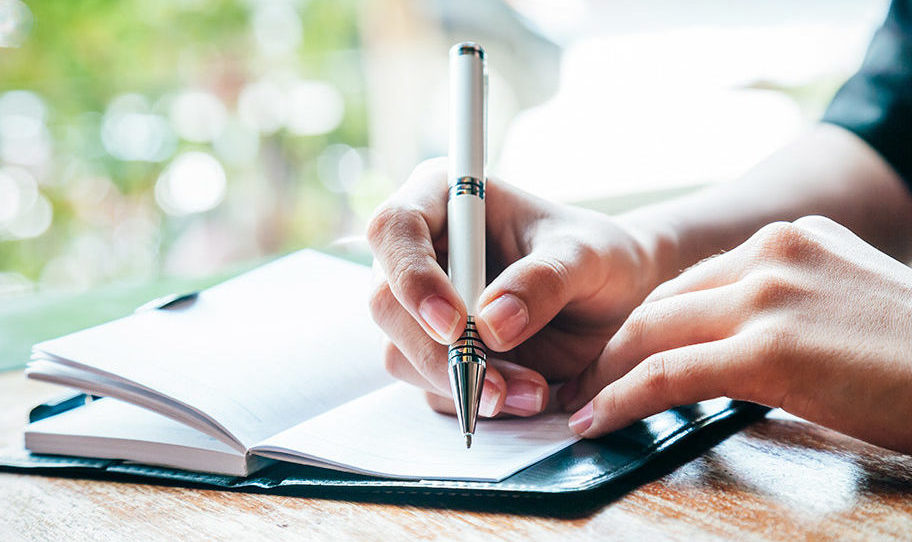 Close up of a person writing in their journal