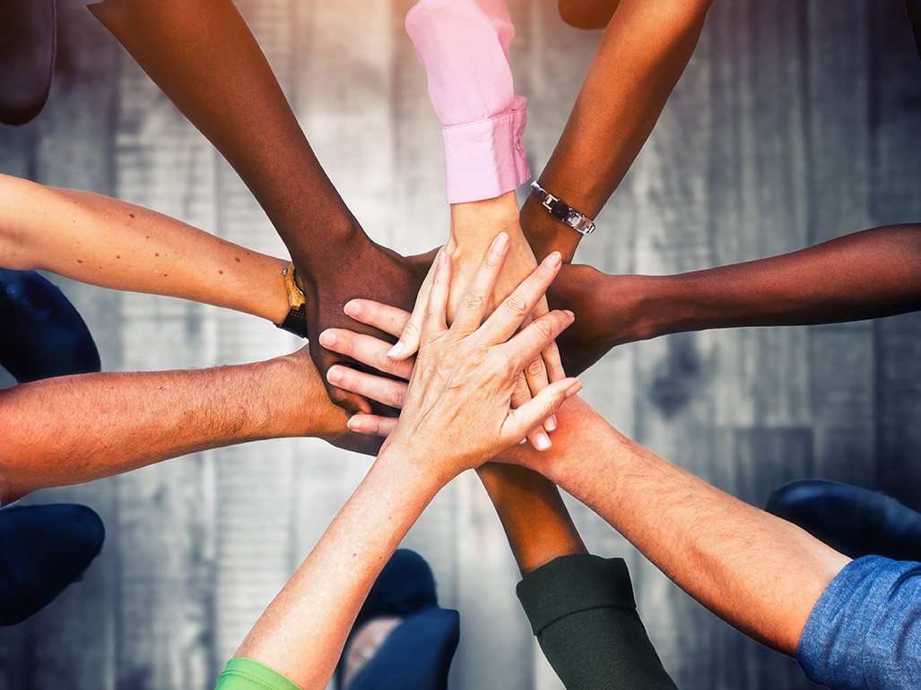 Close up view of diverse people putting their hands together