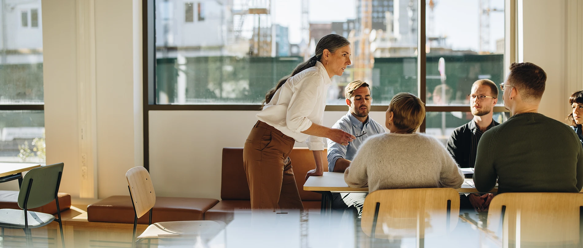 A group of professionals sharing ideas for DEI initiatives around a table in a brightly lit meeting room.