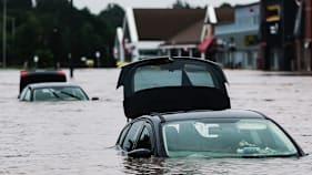 Flooded cars sit in deep water in a parking lot.