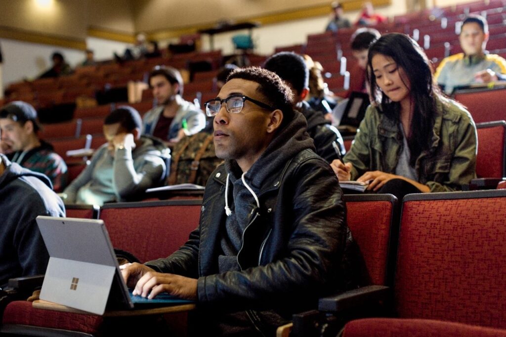 a group of people sitting at a table using a laptop