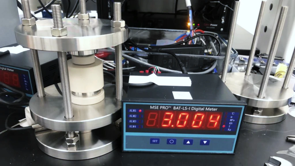 Photograph of a pressure-controlled battery test rig
with a digital device with a display.
