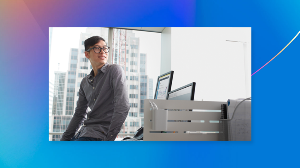 Man looking away from desktop computer with blue background