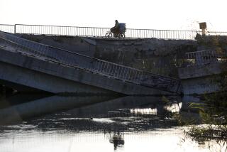 A man on his motorcycle passes by a bridge that links to Lebanon which was destroyed on Oct. 24 by an Israeli airstrike, in Qusair, Syria, Sunday, Oct. 27, 2024. (AP Photo/Omar Sanadiki)