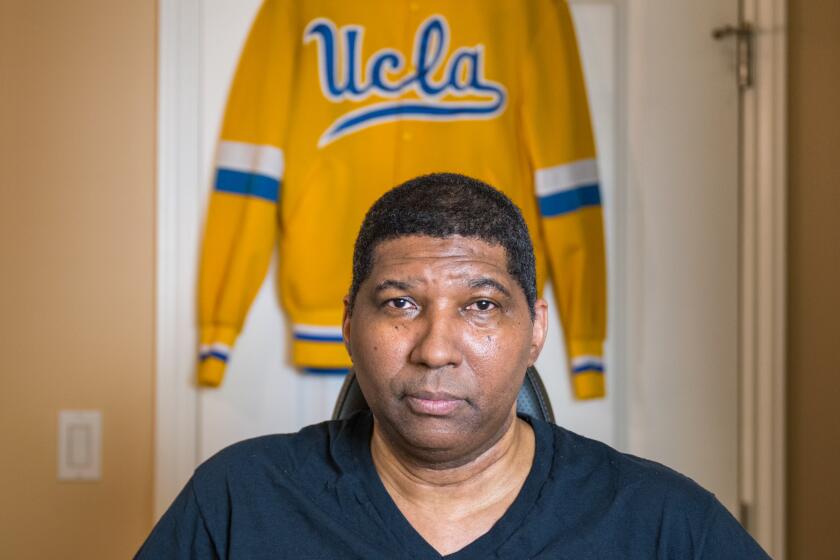 Former UCLA basketball star Rod Foster holds a basketball and sits in his wheelchair in his West L.A. home. 