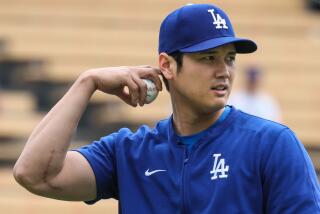 Dodgers two-way player Shohei Ohtani throws warm up pitches in the outfield prior to a game against the Colorado Rockies