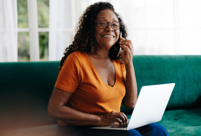  Woman sitting on couch using a laptop and talking on the phone 