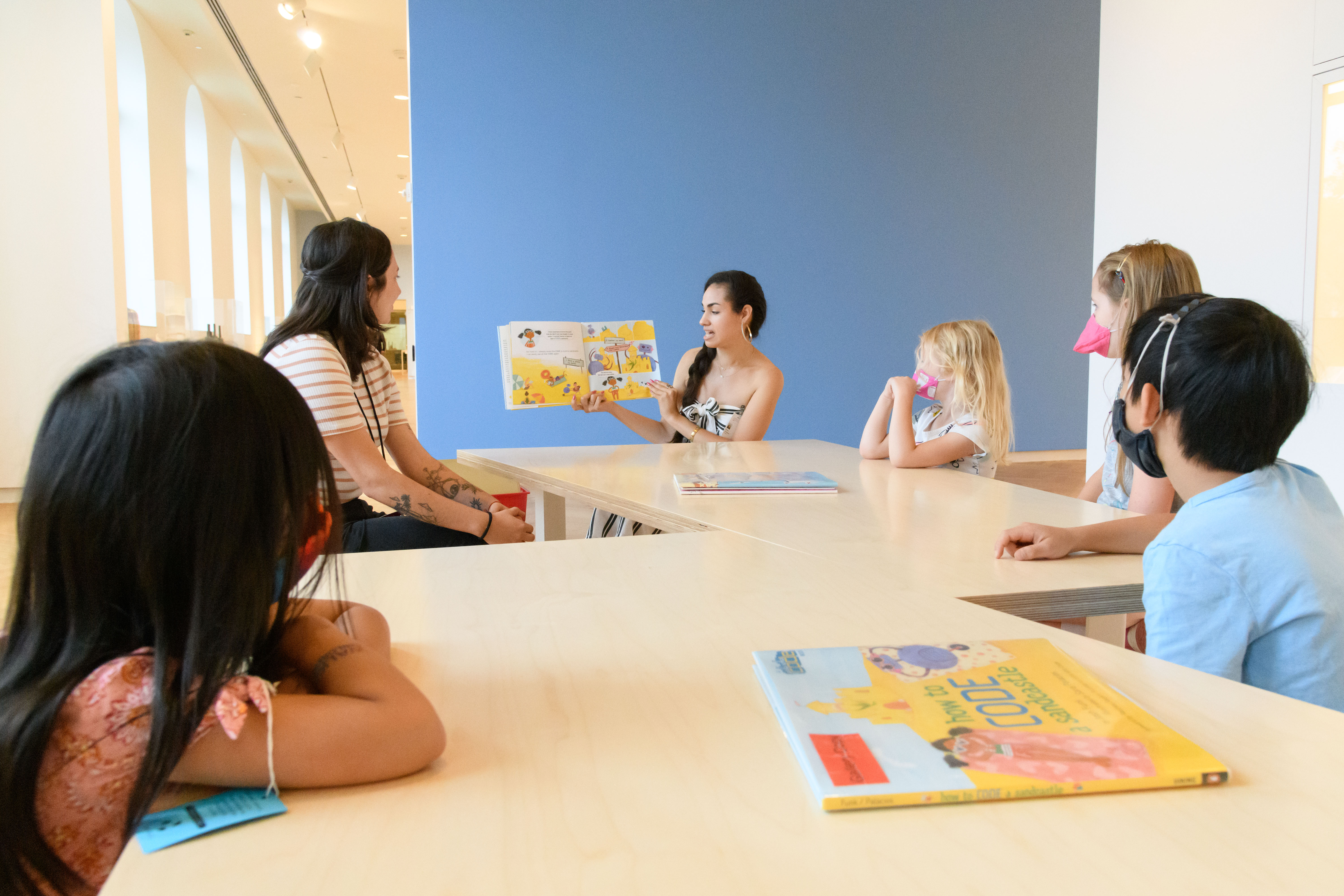 Kids at a table being read to.