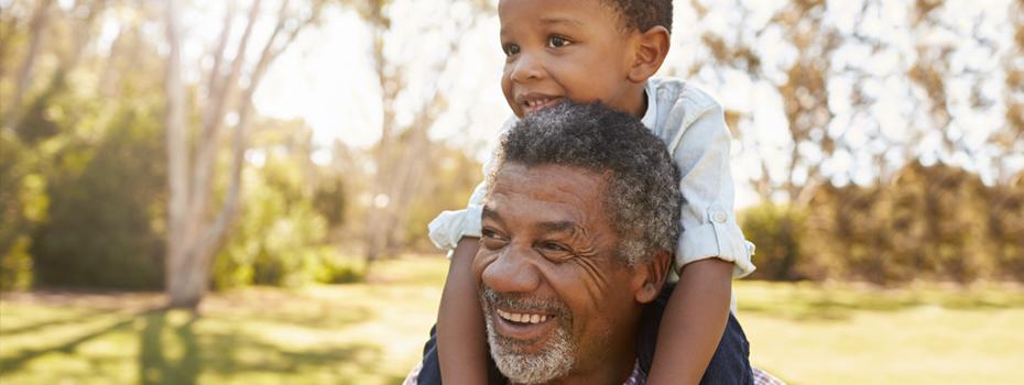 A middle aged man carrying a small child on his shoulders