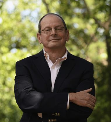 Jonathan Rauch semi-professional headshot, standing with a background of greenery and his arms crossed