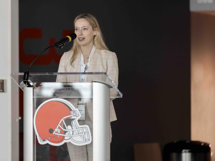 Annabelle Lincoln presenting at SportsLand Summit behind a podium with a Cleveland Browns logo on it