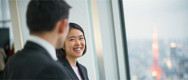 Two persons are smiling and talking.