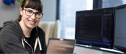 A woman working on her laptop with monitor