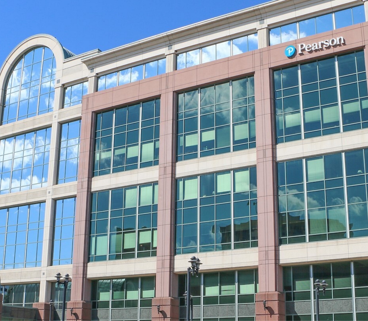 Image of a multi-story modern office building with large glass windows and a "Pearson" sign on the top right corner. 