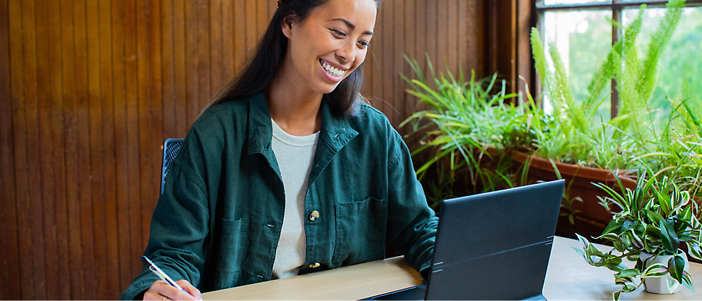 Een vrouw die lacht en op een laptop werkt