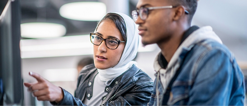 A person and another person looking at computer screen