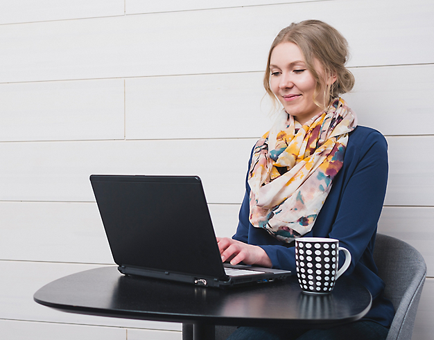 A person sitting at a table smiling and using a computer