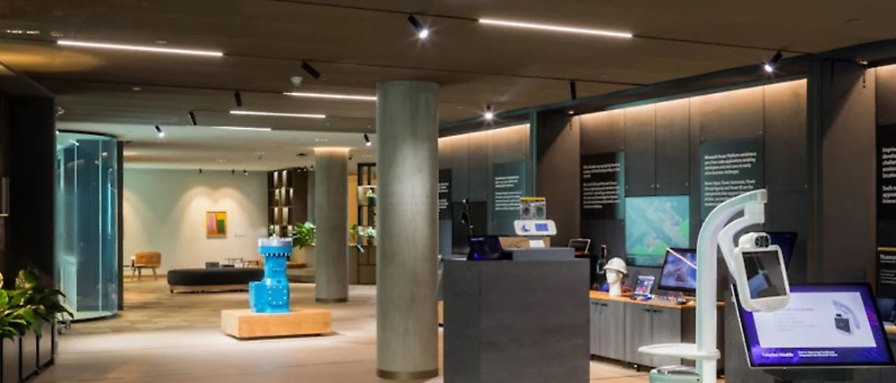 Modern office lobby with information displays, a reception desk on the right, and seating areas