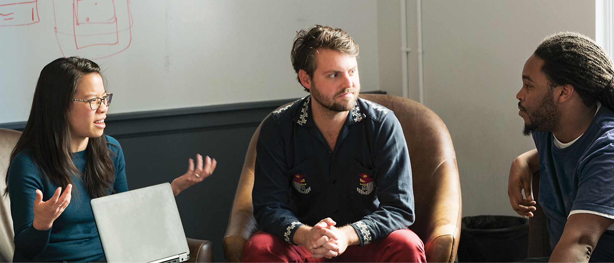 three persons sitting on couch and talking with each other