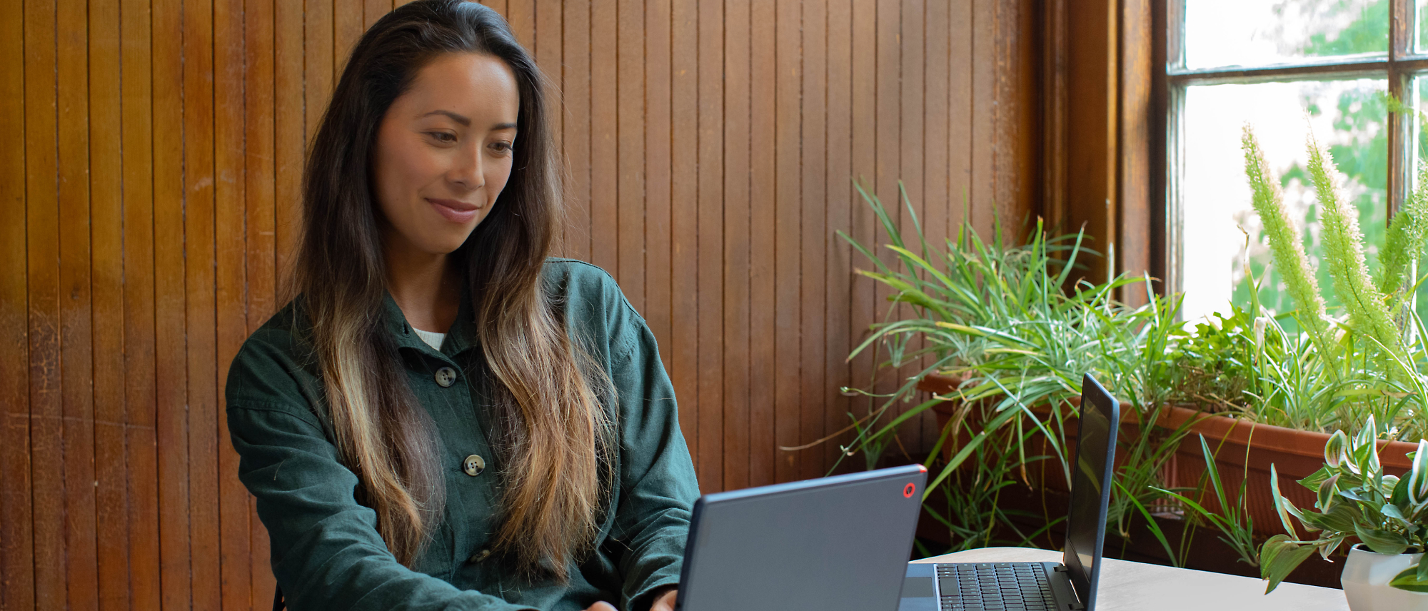 Seorang perempuan sedang duduk dan menggunakan laptop