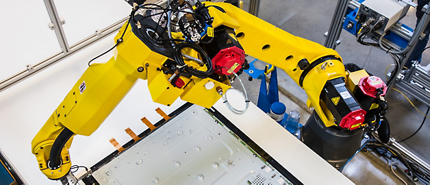 Industriel robotarm udfører præcisionsarbejde på et samlebånd.