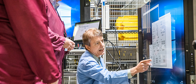 Two people in a control room analyzing data on computer screens.